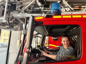 Isabell Rahms sitzt am Steuer eines roten Feuerwehrautos mit Drehleiter bei der Feuerwehr Mainz