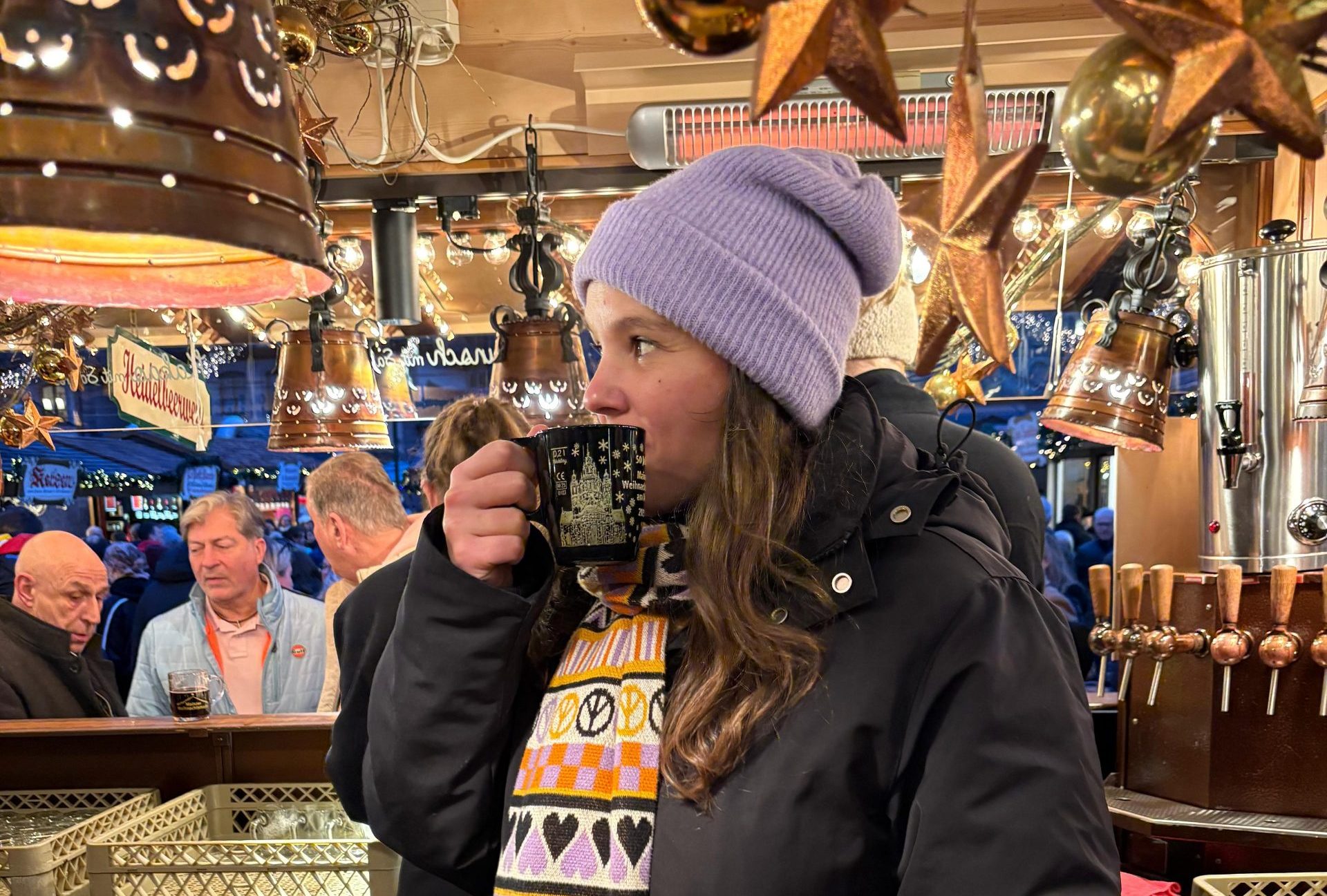 Isabell Rahms am Glühweinstand von Marco Sottile vor den Markthäusern auf dem historischen Weihnachtsmarkt Mainz, mit Tasse Glühwein in der Hand